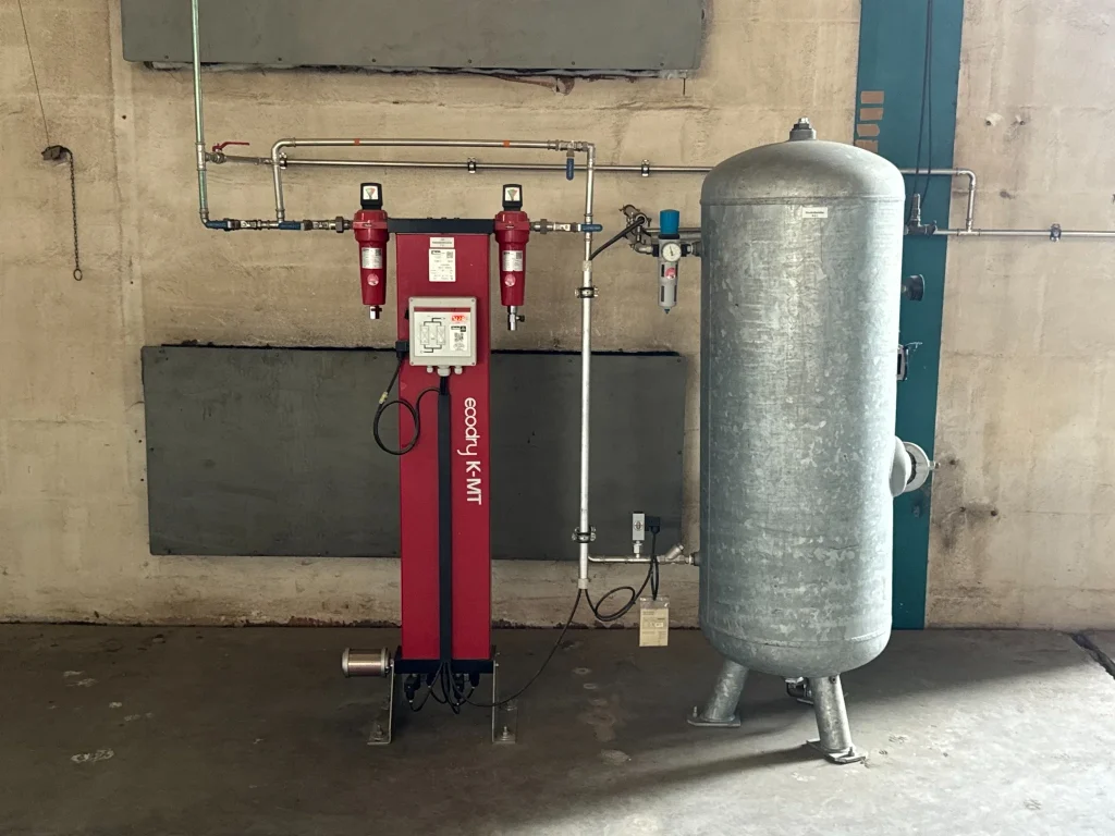 Drucklufttrockner ecodry K-MT mit angeschlossenem Druckluftbehälter und Rohrleitungssystem in einer industriellen Druckluftanlage.