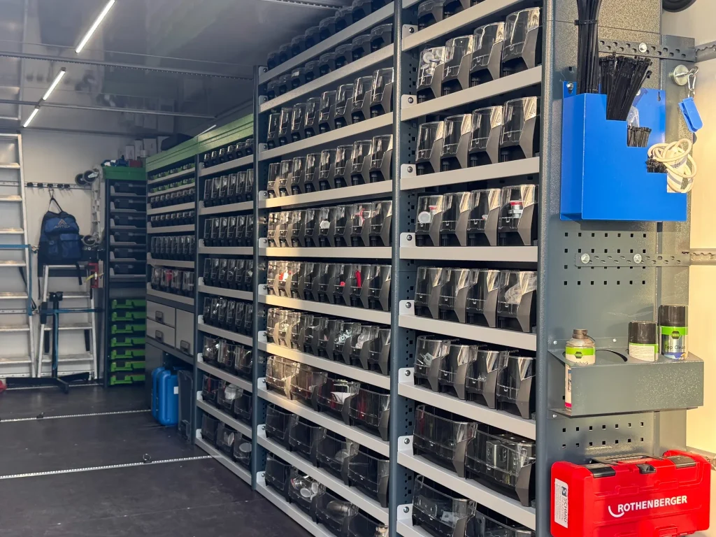 Innenausstattung des Rohrleitungsanhängers mit übersichtlich sortierten Druckluft-Fittings und Montagematerial in Lagerboxen.