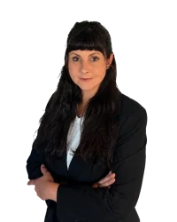Protraitbild einer Frau mit dunklen haaren und Businesskleidung vor weißem Hintergrund.